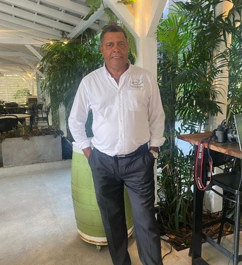 Homme en chemise blanche posant dans un restaurant entouré de plantes