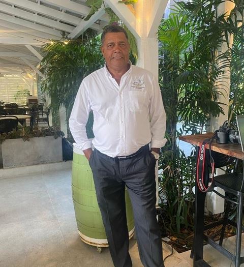 Homme en chemise blanche posant dans un restaurant entouré de plantes