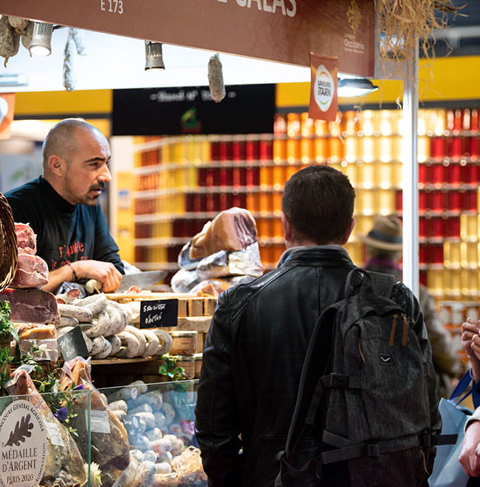 Exposant derriere son stand de charcuterie